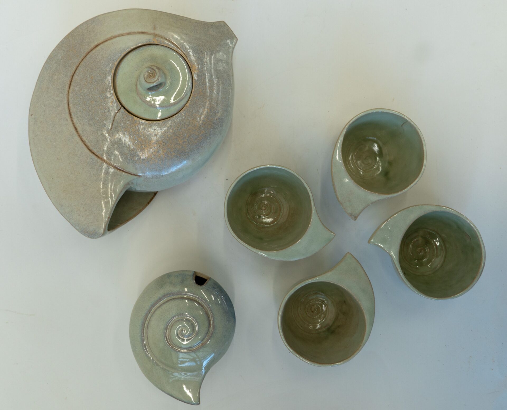 Zdjęcie. Ceramiczny zestaw. Cztery niewielkie miseczki i dwa pojemniki w kształcie muszli. Zdjęcie zrobione z góry.