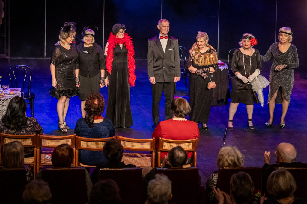 Zdjęcie. Siedem osób w rzędzie na scenie. To aktorzy Teatru bez Suflera podczas ukłonów.