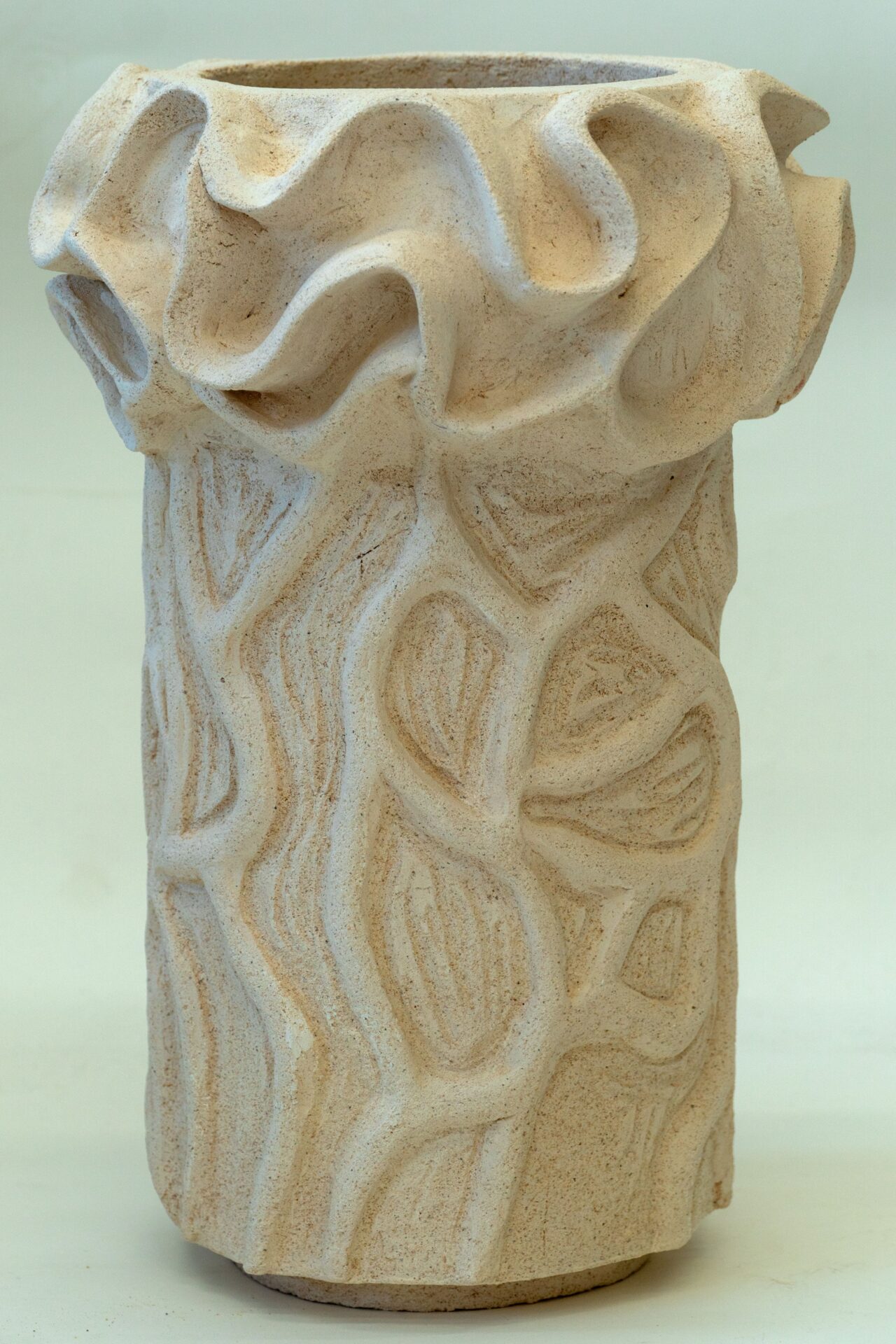 Zdjęcie. Ceramiczna forma w kształcie pionowego walca. Na powierzchni labirynt falowanych linii.