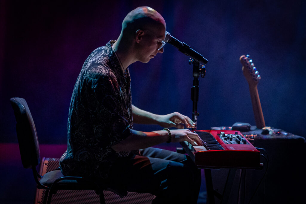 Zdjęcie. Łysy mężczyzna gra na keyboardzie.
