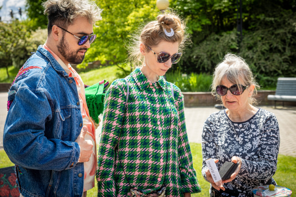 Zdjęcie. Artur Wijata i Agata Buzek patrzą w kierunku niewielkiej rzeczy. Pokazuje im ją niewysoka kobieta o siwych włosach. To Anna Studzińska z Fundacji na Rzecz Zwierząt "Obok nas".